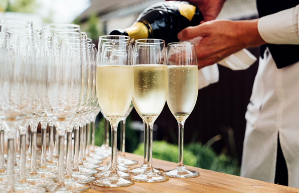 Server pouring glasses of champagne to toast at engagement party celebration